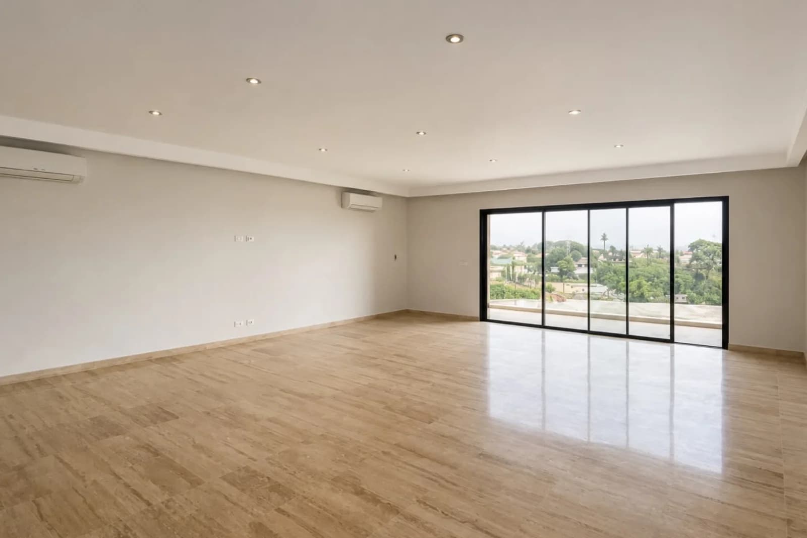 Salon lumineux d'un appartement haut standing à Abidjan, avec vue sur un jardin arboré